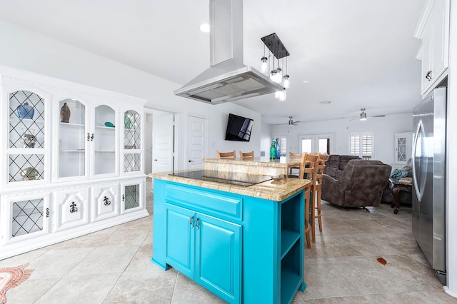 kitchen with a ceiling fan, freestanding refrigerator, blue cabinets, black electric cooktop, and island range hood
