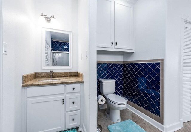 full bathroom with tile walls, toilet, tile patterned flooring, and vanity