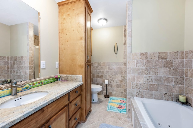 bathroom with tile patterned floors, toilet, vanity, a whirlpool tub, and tile walls