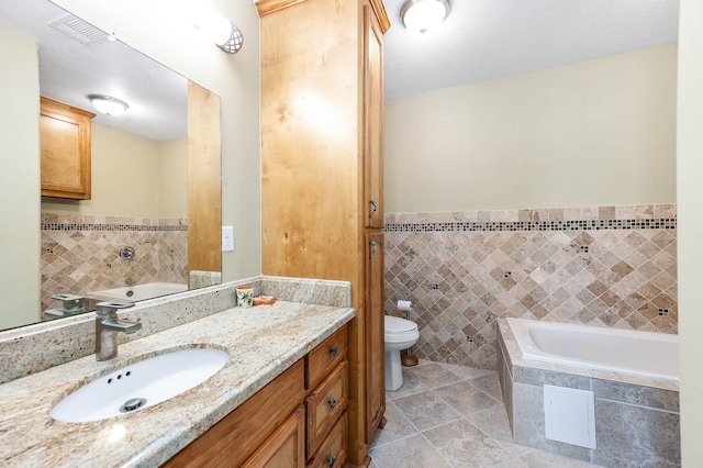 bathroom featuring tile walls, visible vents, toilet, and a garden tub