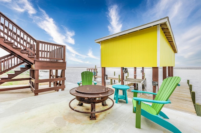 view of patio featuring a water view, a fire pit, a boat dock, and stairway