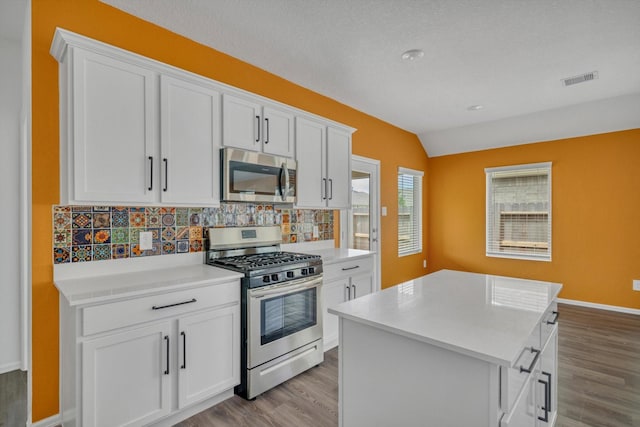 3148 Catalonion Ct, Conroe, TX 77301 - kitchen with stainless steel appliances, wood finished floors, tasteful backsplash, vaulted ceiling, and white cabinetry
