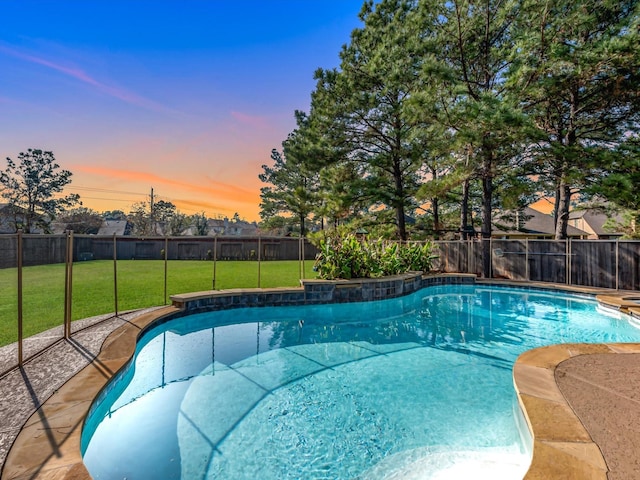 pool at dusk featuring a yard and a fenced backyard