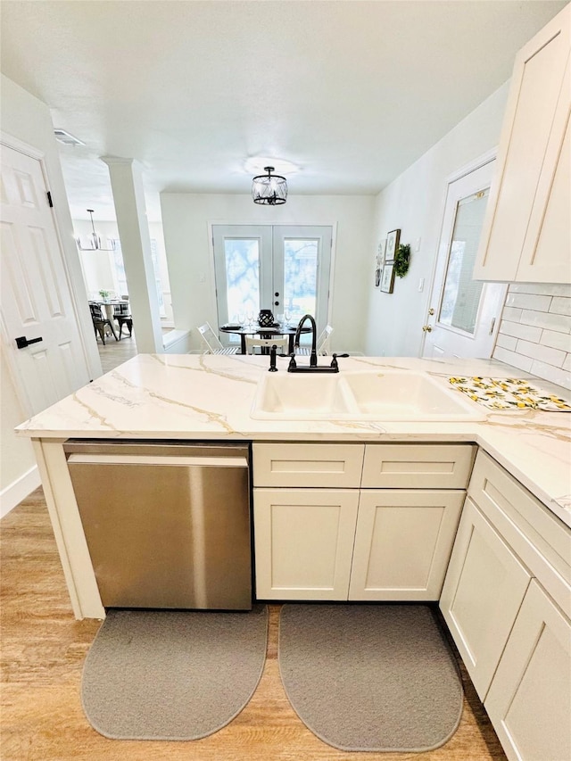 8522 Pearl Lake Dr, Houston, TX 77095 - kitchen with stainless steel dishwasher, a peninsula, light wood-type flooring, french doors, and decorative backsplash