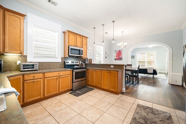 3529 Avenue S, Galveston, TX 77550 - kitchen with light tile patterned floors, stainless steel appliances, arched walkways, visible vents, and a peninsula