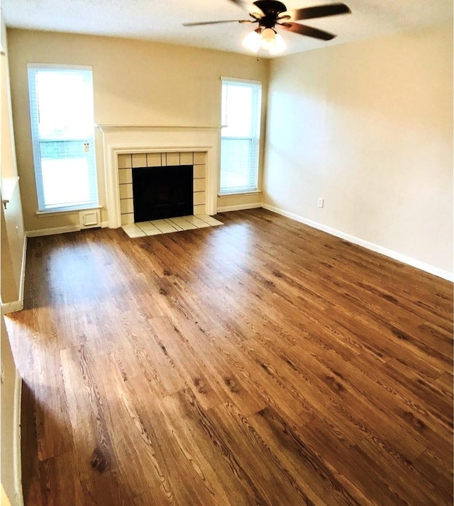 18146 River Sage Dr, Houston, TX 77084 - unfurnished living room with wood finished floors, a ceiling fan, baseboards, and a fireplace