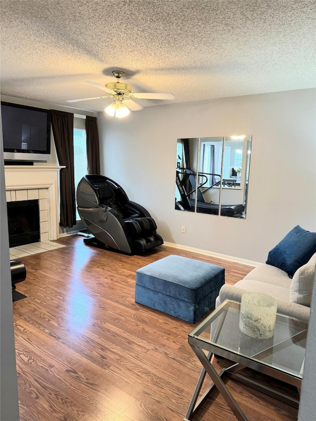 18146 River Sage Dr, Houston, TX 77084 - living room with a textured ceiling, wood finished floors, a fireplace, a ceiling fan, and baseboards