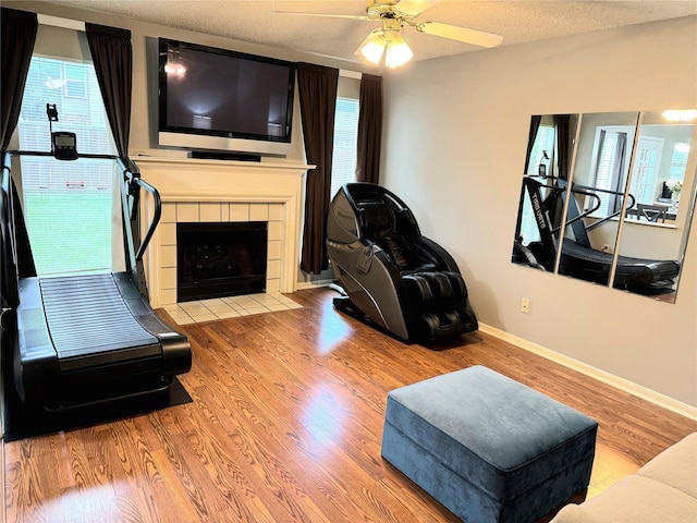 18146 River Sage Dr, Houston, TX 77084 - living area with wood finished floors, a tile fireplace, healthy amount of natural light, baseboards, and a textured ceiling