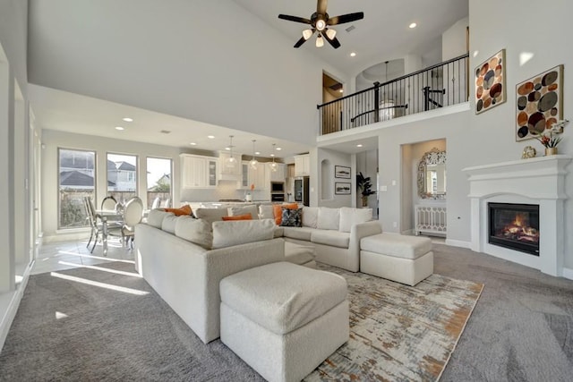 28902 Ridge Valley Ct, Fulshear, TX 77441 - carpeted living area with a glass covered fireplace, recessed lighting, ceiling fan, baseboards, and a towering ceiling
