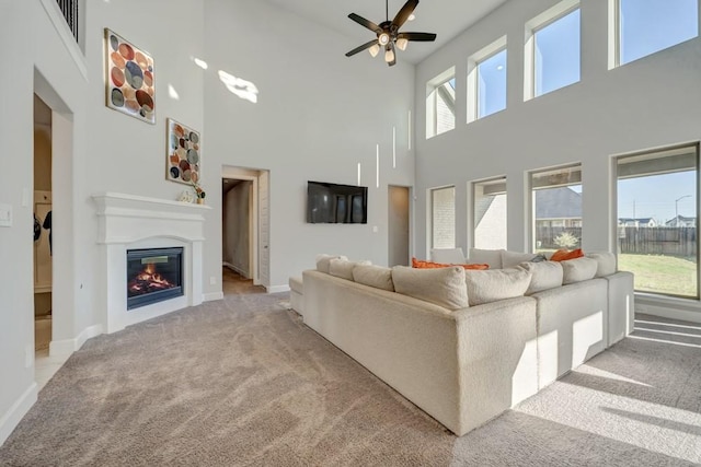 28902 Ridge Valley Ct, Fulshear, TX 77441 - living room featuring a towering ceiling, carpet flooring, ceiling fan, a glass covered fireplace, and baseboards