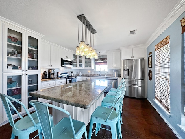 kitchen with stainless steel appliances, a center island, a sink, visible vents, and white cabinets