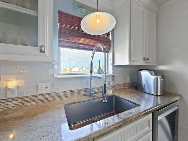 kitchen featuring stainless steel dishwasher, backsplash, a sink, white cabinets, and light stone countertops