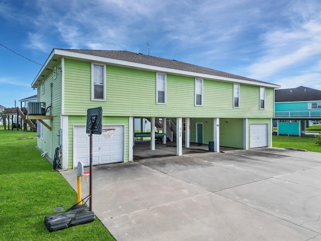 back of property featuring a lawn, concrete driveway, a carport, and an attached garage