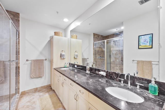 full bath with a stall shower, double vanity, tile patterned flooring, and a sink