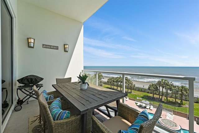 balcony with a beach view, outdoor dining area, and a water view