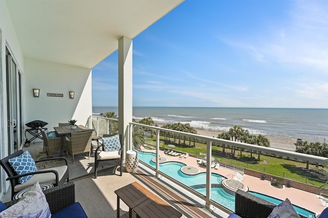 balcony with a water view and a view of the beach