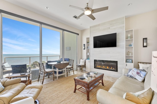 living room featuring a tiled fireplace, built in features, visible vents, ceiling fan, and recessed lighting