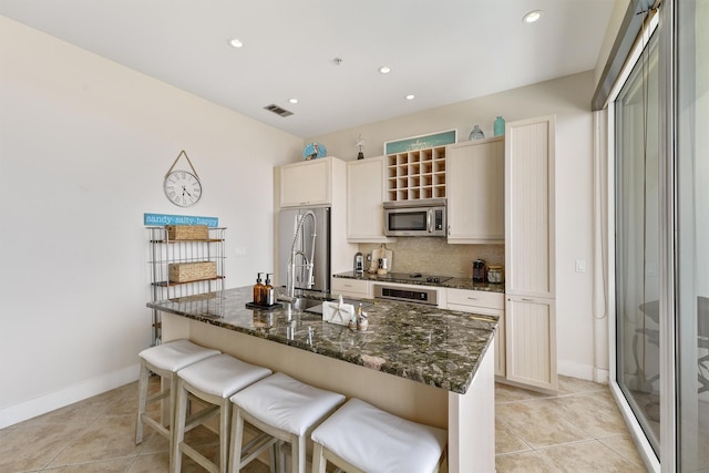 kitchen with light tile patterned flooring, a breakfast bar, stainless steel appliances, tasteful backsplash, and a sink