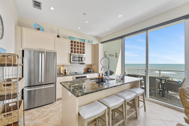 kitchen with dark stone countertops, backsplash, a sink, visible vents, and appliances with stainless steel finishes