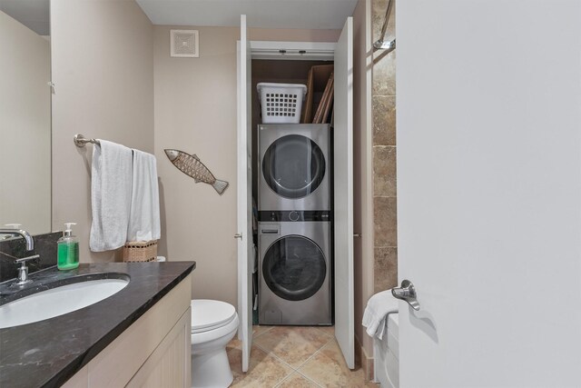 bathroom featuring vanity, toilet, tile patterned floors, stacked washer and dryer, and visible vents
