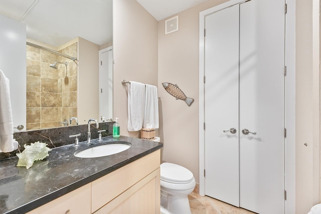 bathroom with tile patterned flooring, vanity, toilet, visible vents, and tiled shower