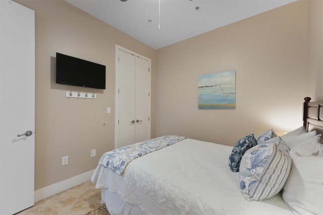 bedroom featuring a ceiling fan, a closet, light tile patterned floors, and baseboards