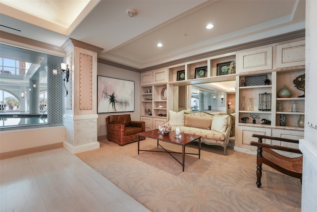 living area featuring a tray ceiling, recessed lighting, light wood-type flooring, ornamental molding, and baseboards