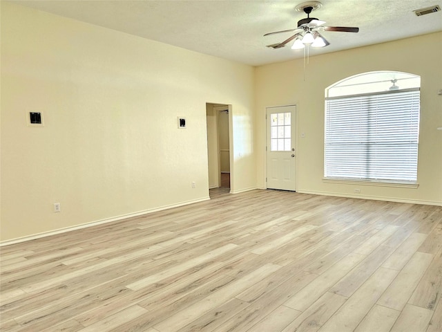 empty room featuring light wood-type flooring, baseboards, visible vents, and ceiling fan