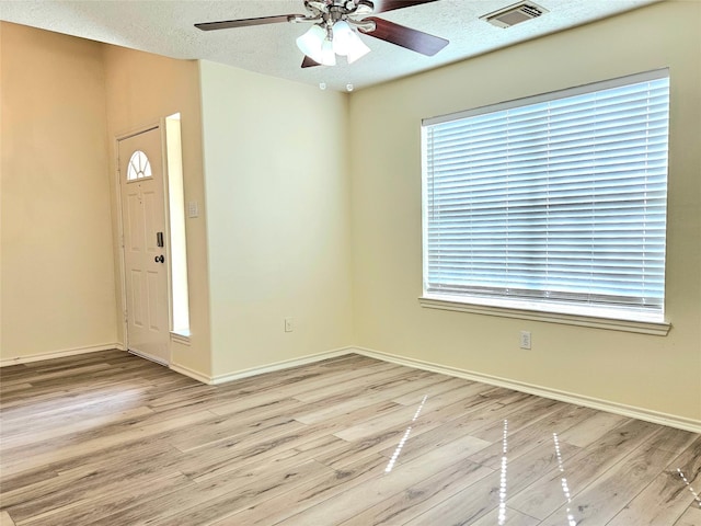 foyer with wood finished floors, visible vents, a ceiling fan, baseboards, and a textured ceiling