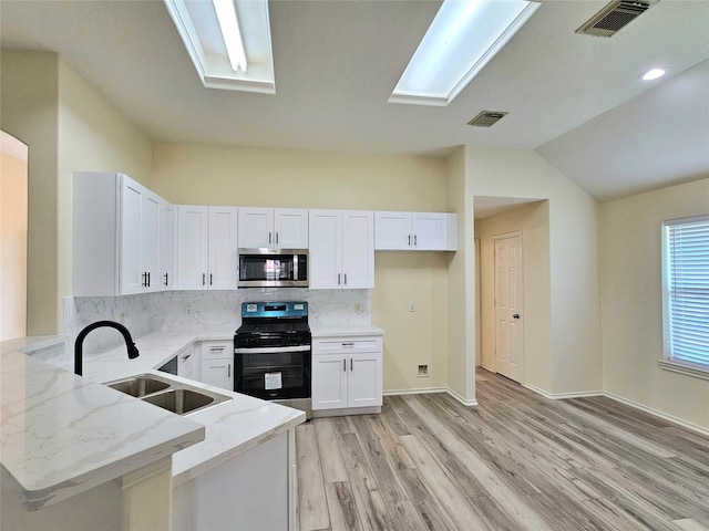 kitchen featuring light stone counters, a sink, light wood-type flooring, stainless steel appliances, and white cabinetry