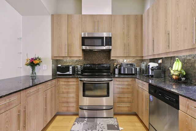 kitchen featuring appliances with stainless steel finishes, dark stone countertops, and light brown cabinets