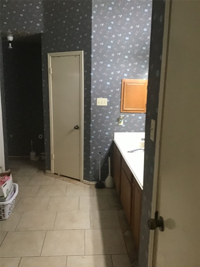 bathroom with wallpapered walls, tile patterned flooring, and vanity