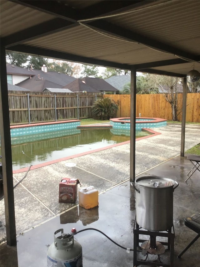 view of patio featuring a fenced backyard, a fenced in pool, and an in ground hot tub