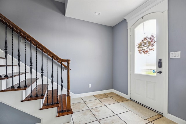 tiled entryway featuring baseboards and stairs
