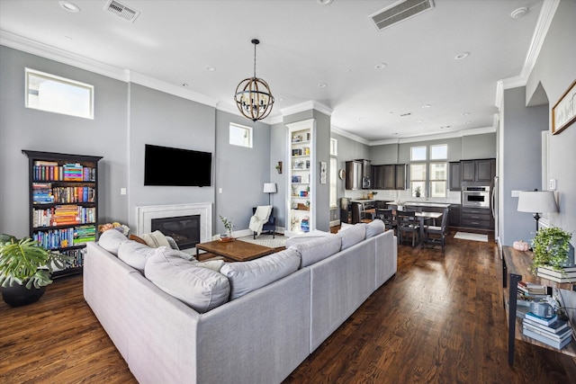 living room with dark wood-type flooring, visible vents, a glass covered fireplace, and crown molding