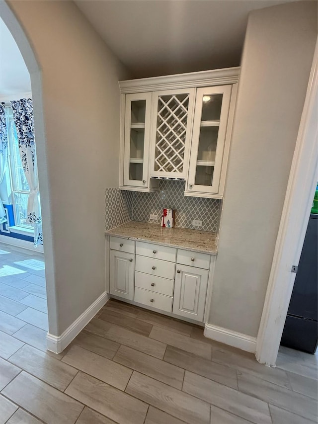 29431 Amber Meadows Ct, Katy, TX 77494 - bar with decorative backsplash, baseboards, a bar, wood finish floors, and arched walkways
