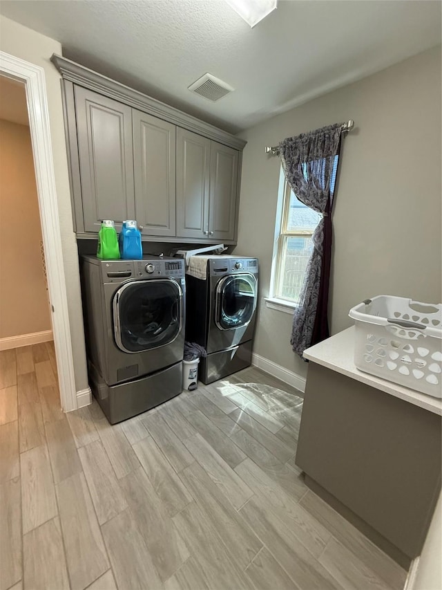 29431 Amber Meadows Ct, Katy, TX 77494 - clothes washing area with visible vents, baseboards, wood finish floors, washing machine and dryer, and cabinet space