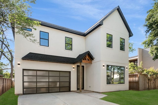 modern farmhouse style home with a garage, roof with shingles, stucco siding, and fence