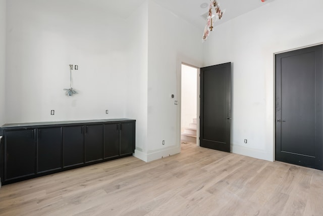 interior space featuring high vaulted ceiling, light wood-style floors, and baseboards