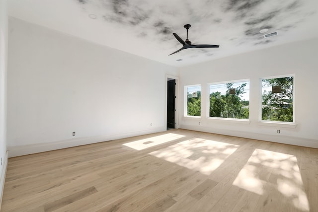 empty room featuring light wood-type flooring, visible vents, baseboards, and a ceiling fan