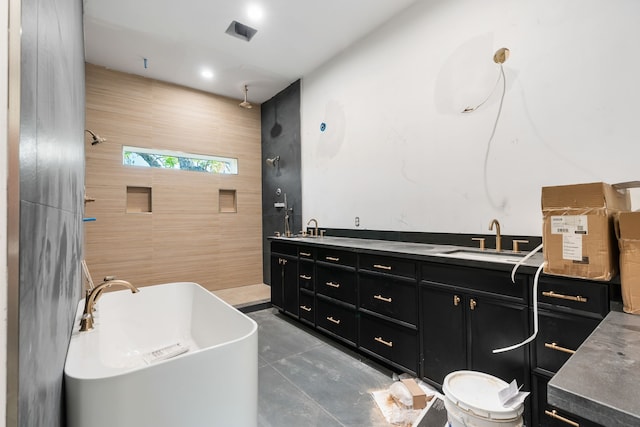 bathroom with a freestanding bath, double vanity, a tile shower, and a sink