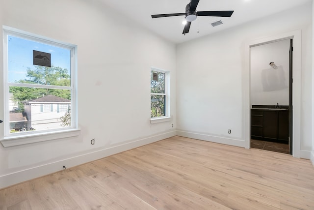 spare room with ceiling fan, visible vents, baseboards, and wood finished floors