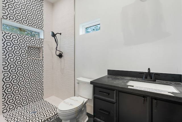 full bath featuring a tile shower, toilet, and vanity