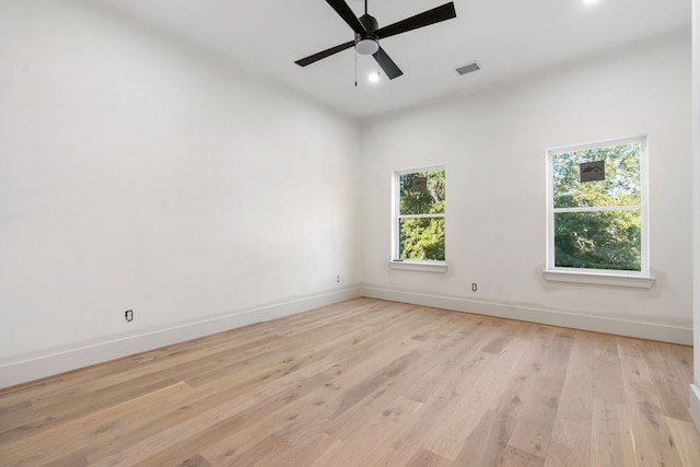 spare room with visible vents, a wealth of natural light, light wood-style floors, and baseboards