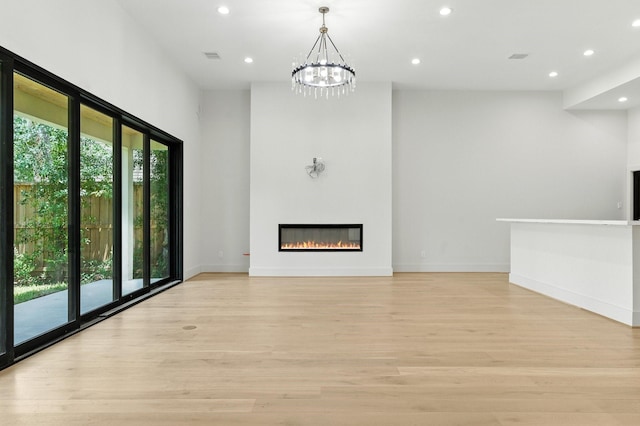 6536 Community Dr, West University Place, TX 77005 - unfurnished living room with recessed lighting, light wood finished floors, a glass covered fireplace, and a chandelier