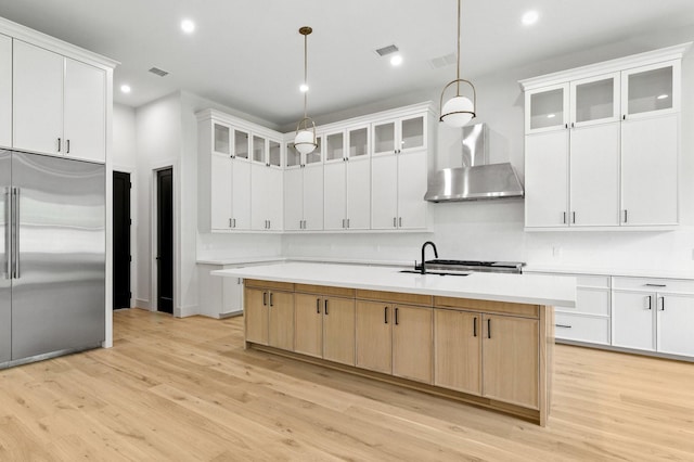 6536 Community Dr, West University Place, TX 77005 - kitchen featuring stainless steel built in refrigerator, wall chimney exhaust hood, light wood-style floors, a center island with sink, and recessed lighting