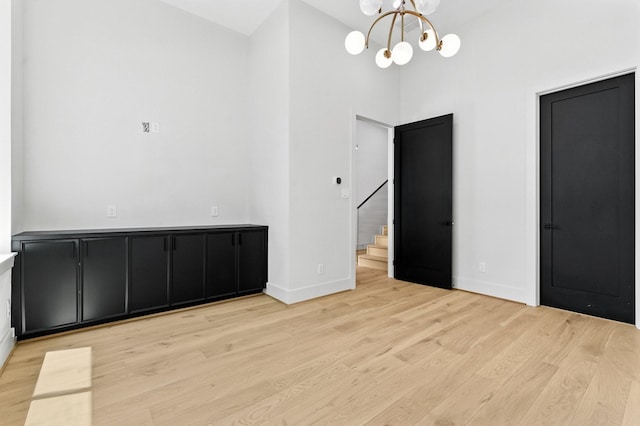 6536 Community Dr, West University Place, TX 77005 - unfurnished dining area featuring a chandelier, wood finished floors, stairs, and a towering ceiling