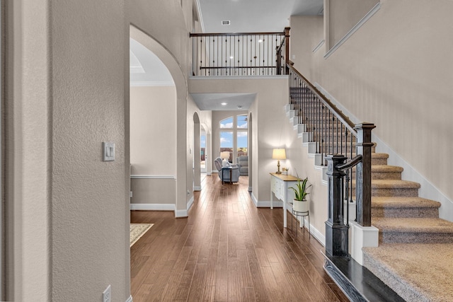 2316 Iron Ridge Ln, Friendswood, TX 77546 - foyer entrance with a high ceiling, a textured wall, wood-type flooring, arched walkways, and stairway
