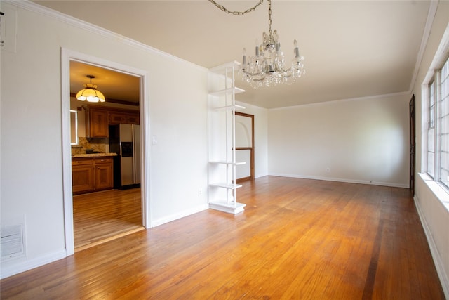 6038 Belcrest St, Houston, TX 77033 - spare room featuring a chandelier, light wood-style floors, baseboards, and ornamental molding