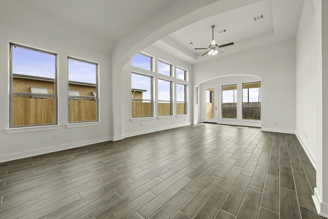 10403 Shining Dawn Way, Richmond, TX 77406 - unfurnished living room featuring ceiling fan, a tray ceiling, dark wood-style flooring, and baseboards